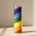 Bougie arc-en-ciel chakras posée sur un meuble en bois fond clair épuré